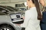 leaseadviseur laat in auto showroom op laptop aan klant de videopagina op de website van financial lease for you zien