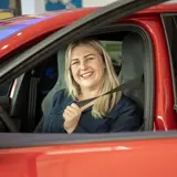 blije klant die in auto gordel omdoet nadat ze auto gekocht heeft